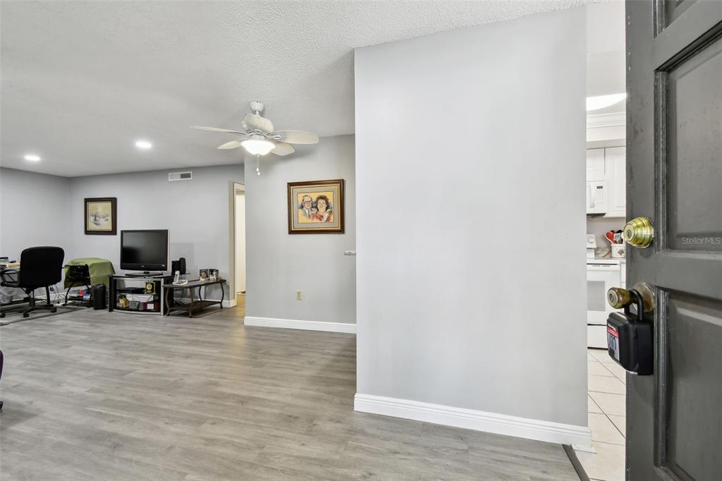 A view from an entryway into a living room with gray flooring and a ceiling fan — 2650 COUNTRYSIDE BOULEVARD UNIT C309, CLEARWATER, FL