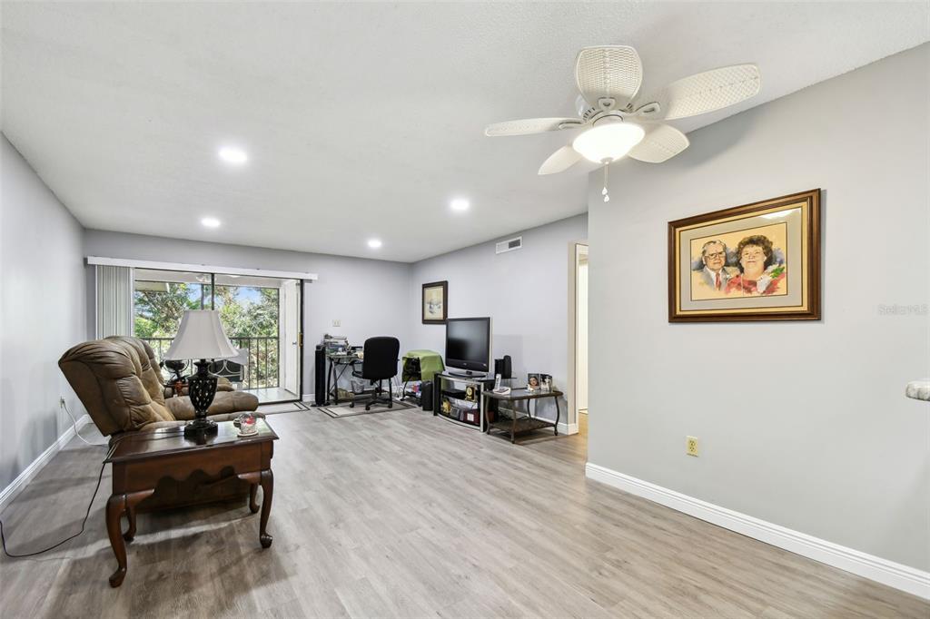 A living room features light gray wood-look flooring, a ceiling fan, and a sliding glass door — 2650 COUNTRYSIDE BOULEVARD UNIT C309, CLEARWATER, FL