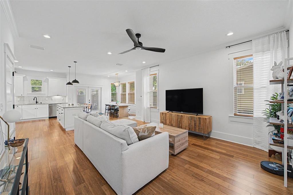 An open-concept living room and kitchen feature hardwood floors, white cabinetry, and a ceiling fan — 911 E OSBORNE AVENUE UNIT A, TAMPA, FL