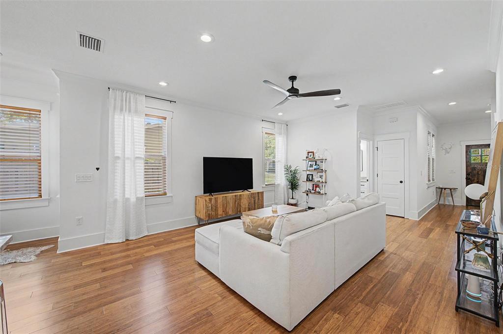 A living room features white walls, hardwood floors, a white sectional sofa, and a television — 911 E OSBORNE AVENUE UNIT A, TAMPA, FL