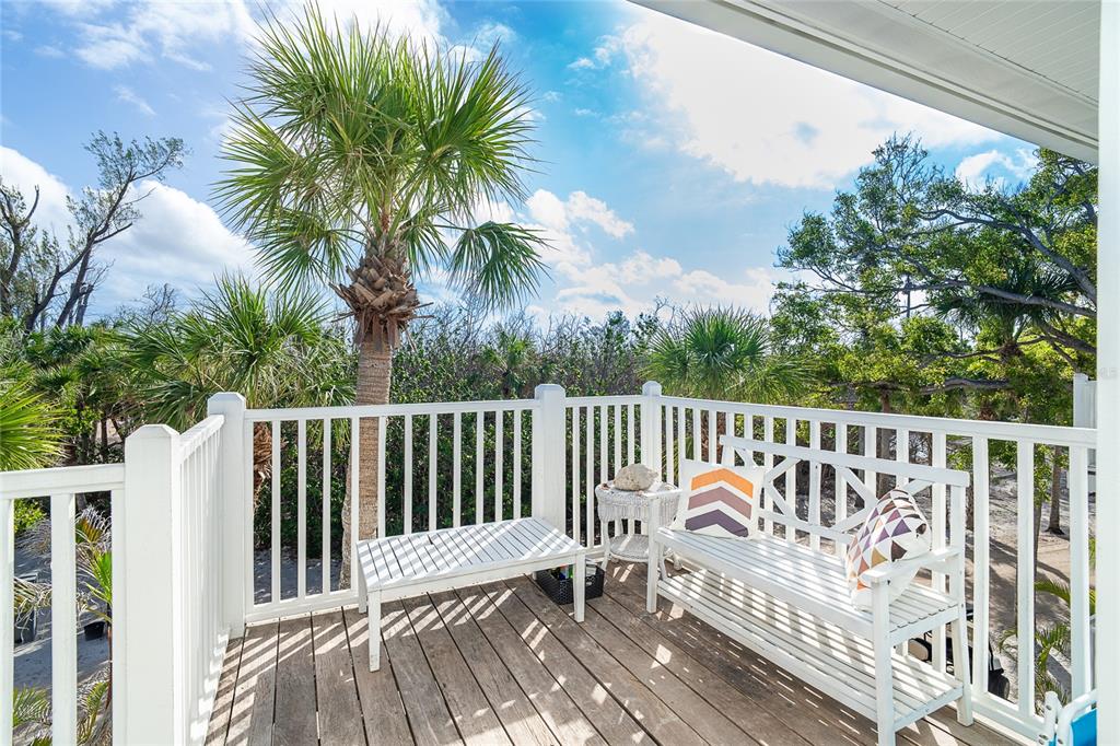 A wooden deck features a white bench, a small table, and a palm tree view — 7536 PALM ISLAND DRIVE S UNIT 1522, PLACIDA, FL