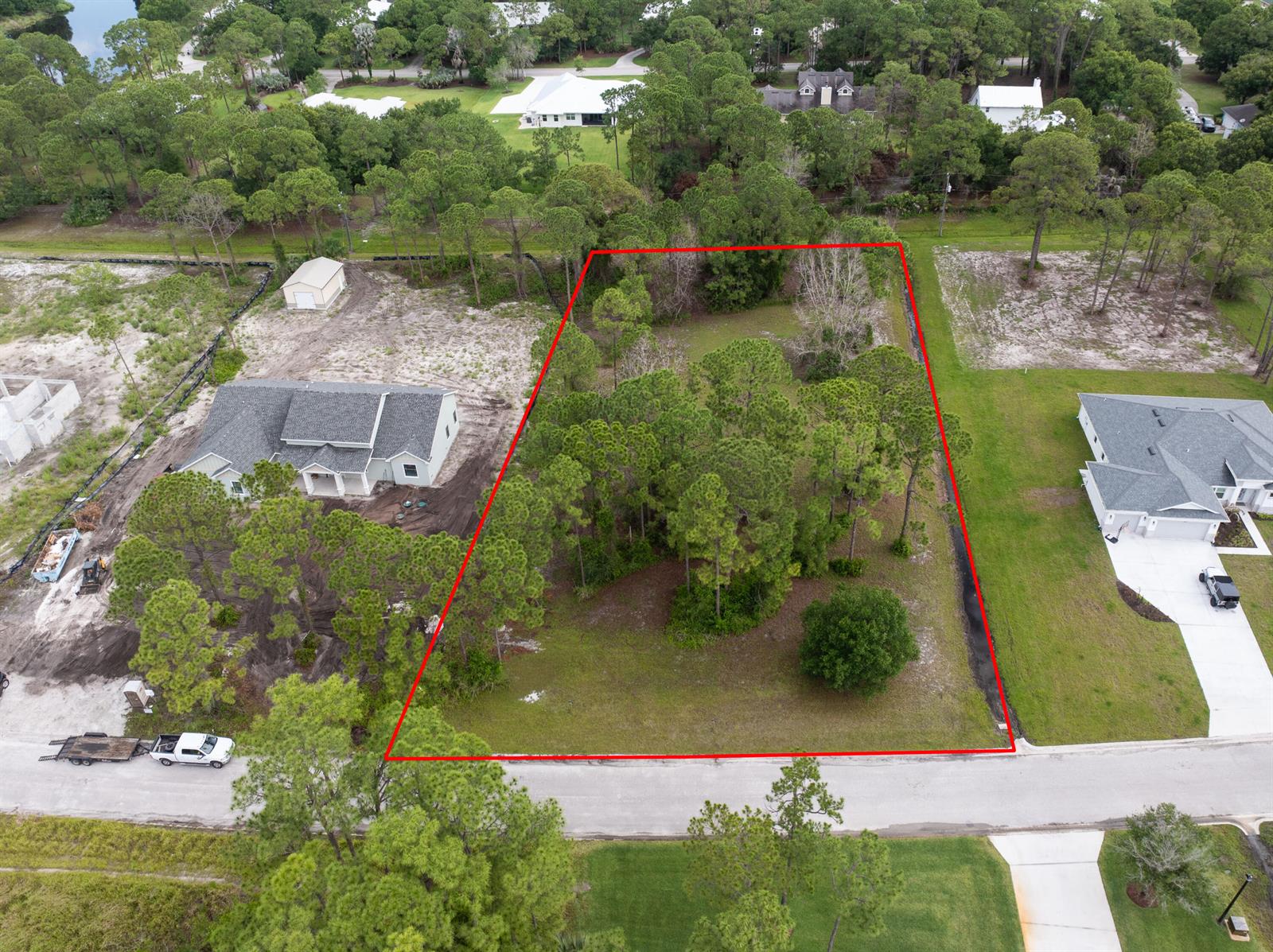 An aerial view shows a vacant, wooded residential lot outlined in red between two houses — 10638 Sugar Pine Drive, Fort Pierce FL 34945, FORT PIERCE, FL