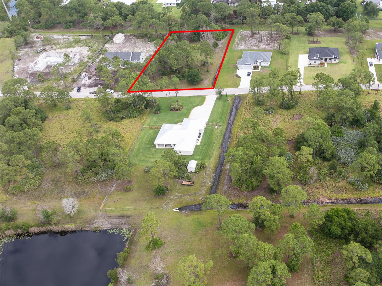 An aerial view shows a wooded, rectangular vacant lot outlined in red along a road — 10638 Sugar Pine Drive, Fort Pierce FL 34945, FORT PIERCE, FL