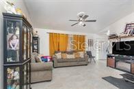 A living room features a beige sofa, a dark display cabinet, and a wall-mounted television — 630 HOBSON TERRACE, DELTONA, FL