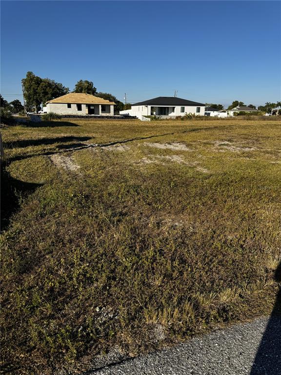 A vacant grassy lot sits in front of two newly constructed houses under a clear sky — 1715 NE 13TH TERRACE, CAPE CORAL, FL