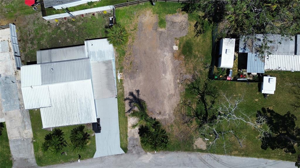 An aerial view shows a house with a metal roof next to a cleared dirt lot — 6828 EDGEWATER DRIVE, NEW PORT RICHEY, FL