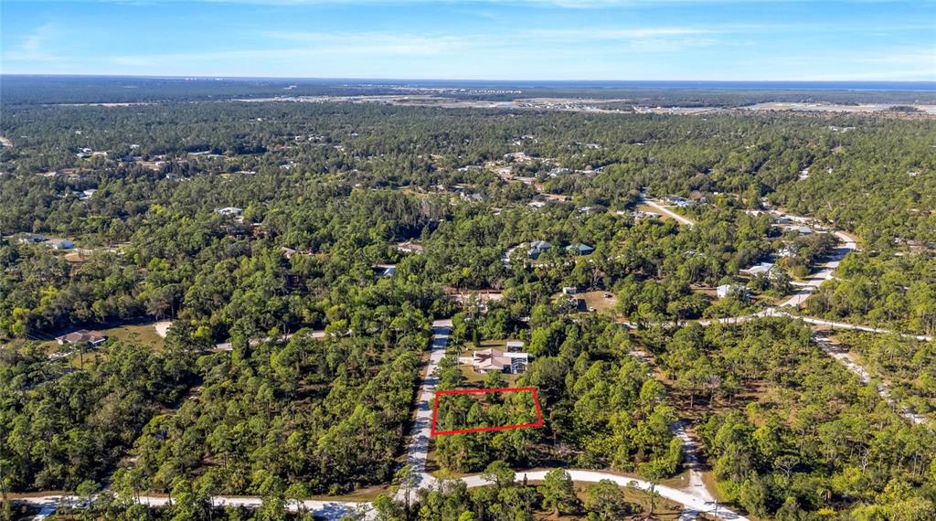 An aerial view shows a rectangular plot of land outlined in red amidst wooded surroundings — 28118 INCHON AVENUE, PUNTA GORDA, FL