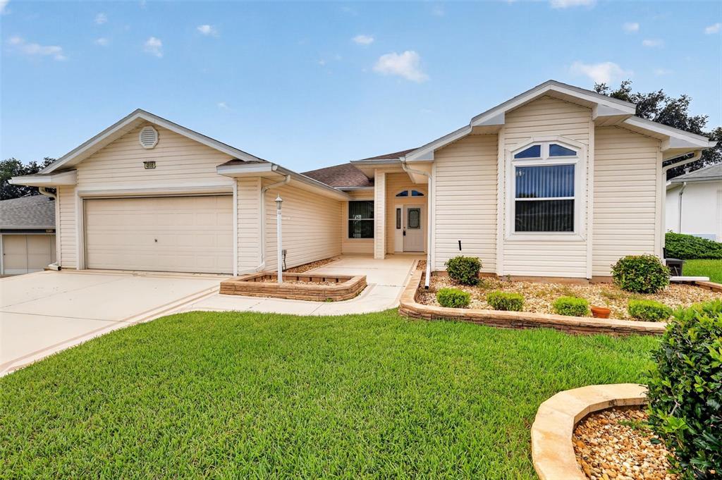 A single-story house with beige siding, a two-car garage, and a landscaped front yard — 4808 KILT COURT, LEESBURG, FL