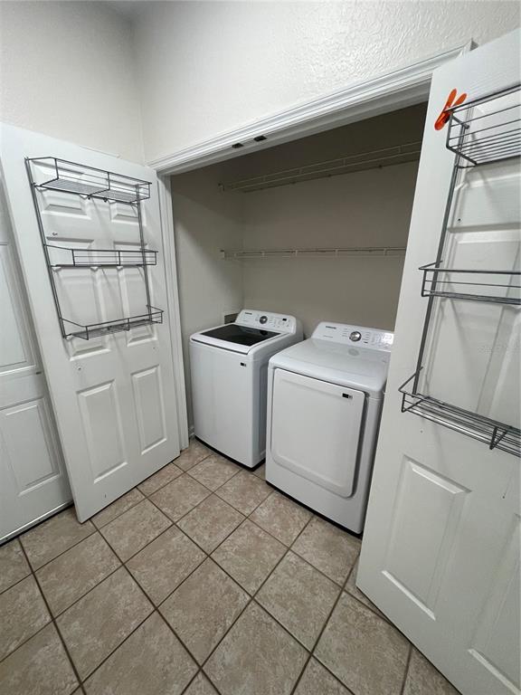 A laundry room features a washer and dryer, wire shelving, and over-the-door storage racks — 13536 TURTLE MARSH LOOP UNIT 512, ORLANDO, FL
