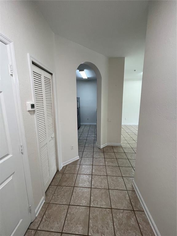 A tiled hallway leads through an arched doorway toward a kitchen with light-colored walls — 13536 TURTLE MARSH LOOP UNIT 512, ORLANDO, FL