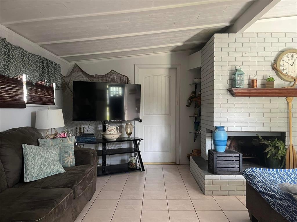A living room features a white brick fireplace, a dark sofa, and a television stand — 1529 W RIVER LANE, TAMPA, FL