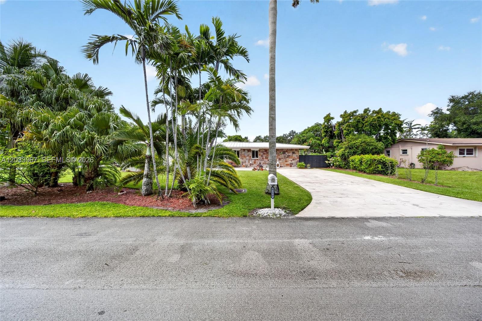 A single-story house with a stone facade sits behind a palm-filled lawn and driveway — 8250 SW 118th Ter, Miami FL 33156, MIAMI, FL