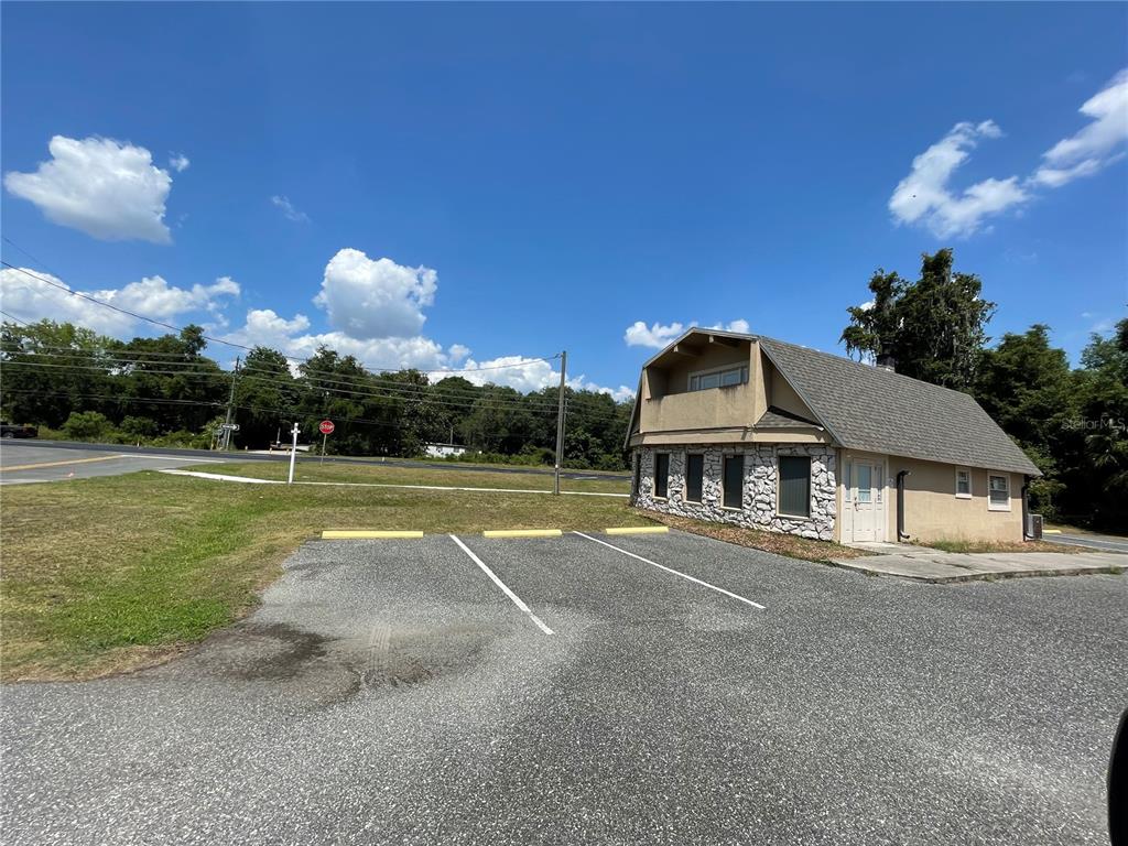 A small, two-story building with stone siding sits next to an asphalt parking lot — 5205 CR 171 - SR 44, WILDWOOD, FL