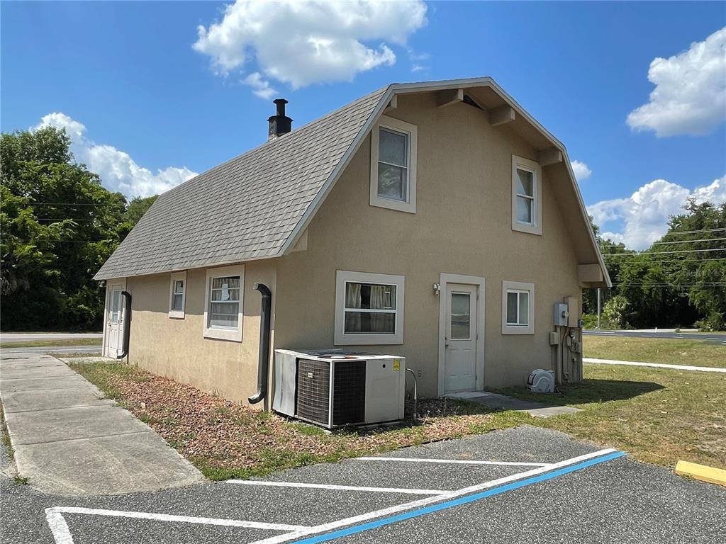 A two-story building with a gambrel roof, beige stucco siding, and an exterior HVAC unit — 5205 CR 171 - SR 44, WILDWOOD, FL