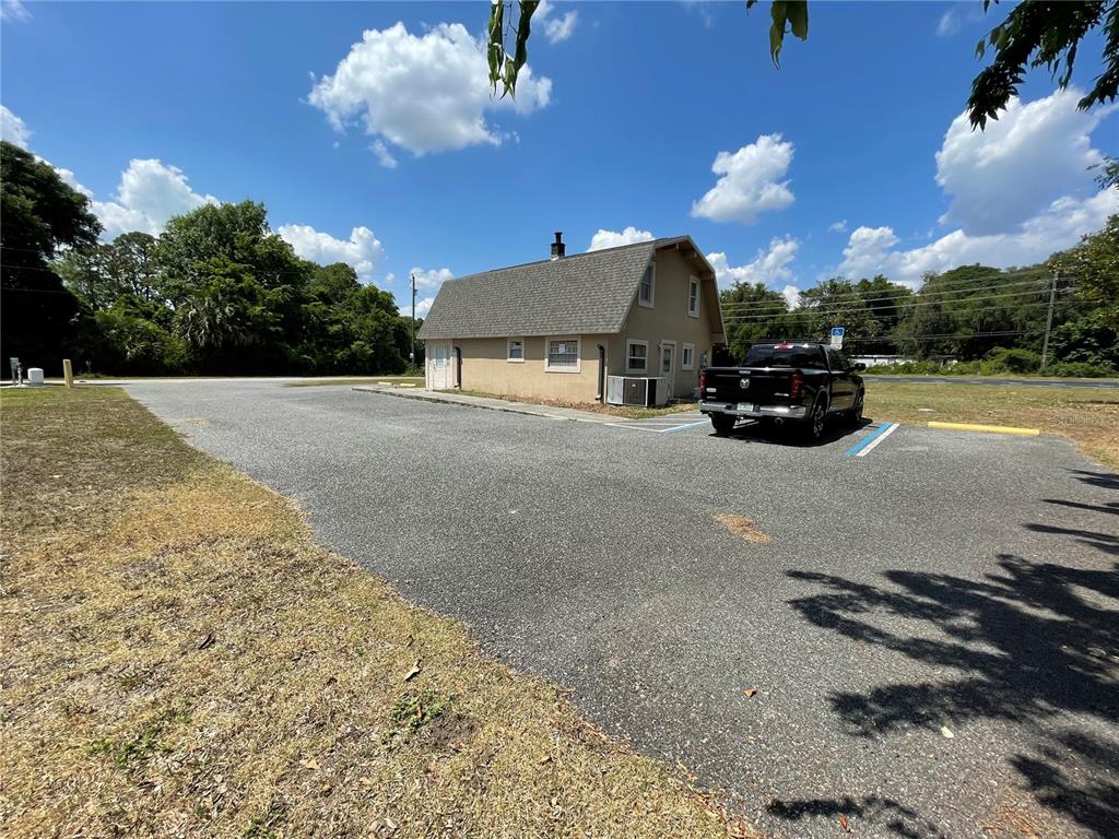 A tan building with a gambrel roof sits on an asphalt parking lot — 5205 CR 171 - SR 44, WILDWOOD, FL