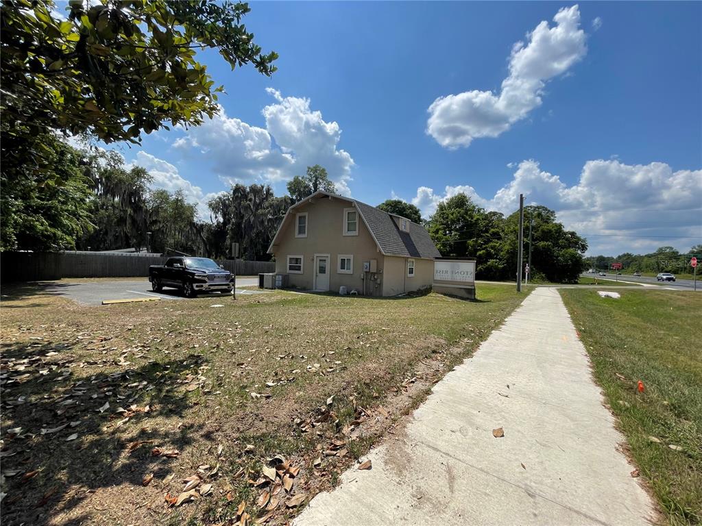A tan two-story building with a parking lot and sidewalk sits under a blue sky — 5205 CR 171 - SR 44, WILDWOOD, FL