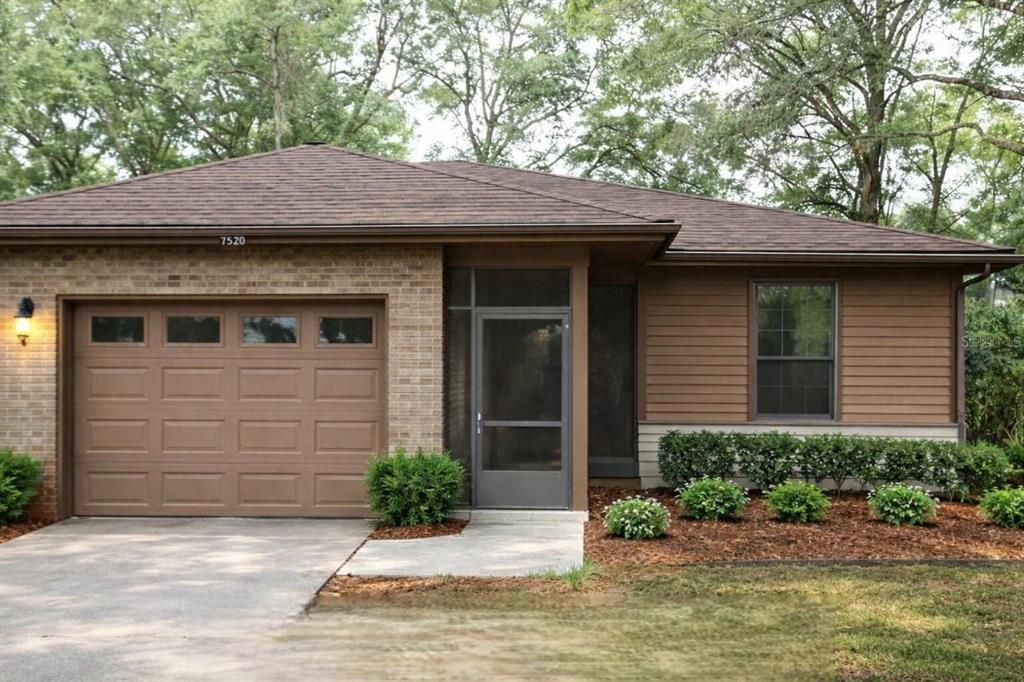 A single-story house with a brick and wood exterior, a garage, and a screened entryway — 7520 COLONY COVE LANE, JACKSONVILLE, FL