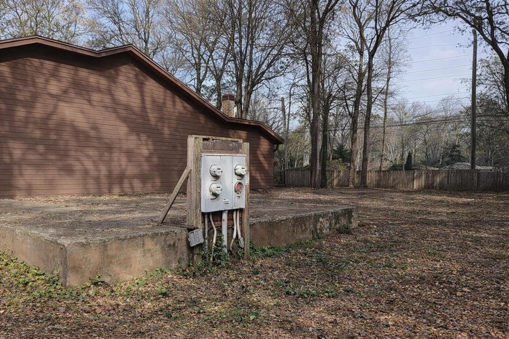 A concrete slab foundation sits in a yard next to a brown wooden building exterior — 7520 COLONY COVE LANE, JACKSONVILLE, FL