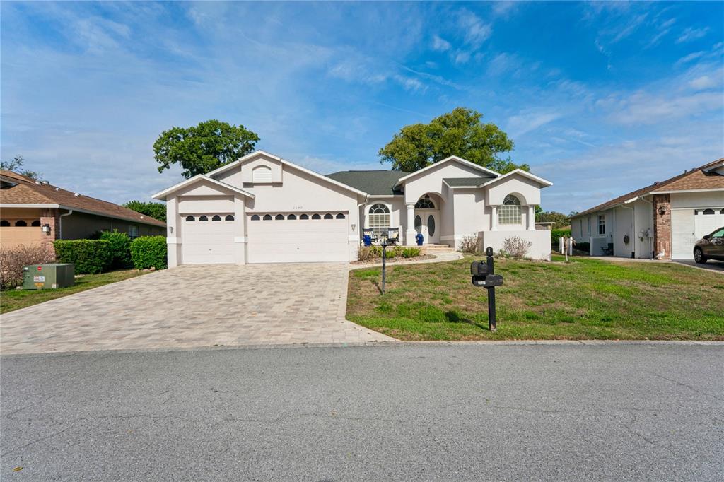 A single-story house with a paved driveway, three-car garage, and a light-colored stucco exterior — 2047 OVERBROOK LANE, SPRING HILL, FL