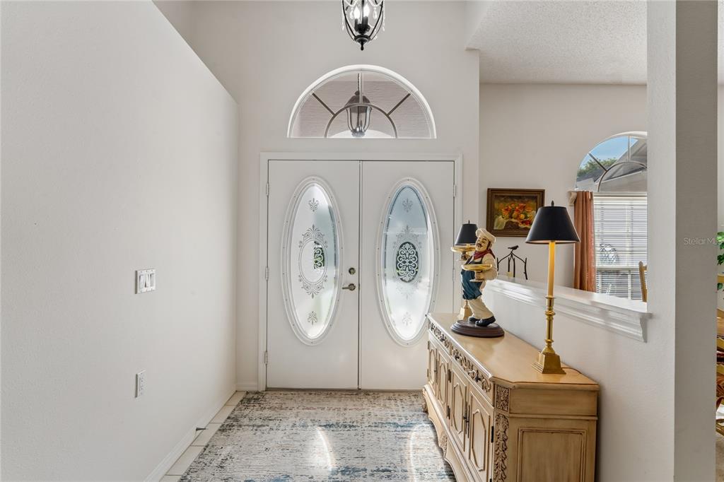 An entryway features double doors with oval glass inserts, a console table, and a rug — 2047 OVERBROOK LANE, SPRING HILL, FL