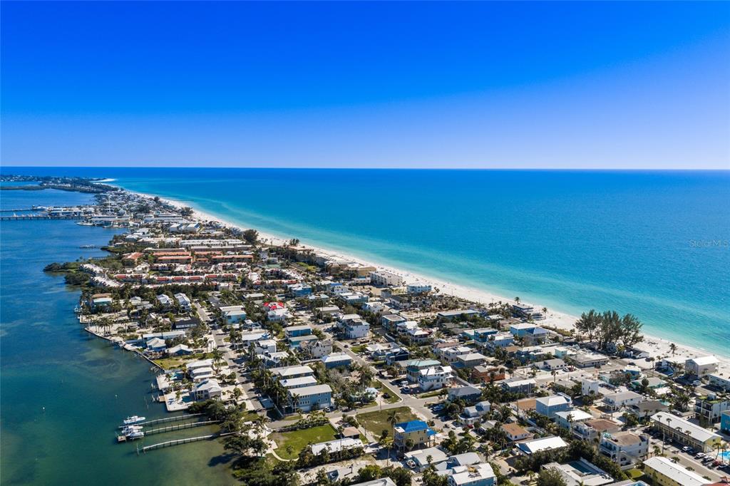 An aerial view shows a coastal neighborhood with houses situated between a bay and beach — 300 23RD STREET N, BRADENTON BEACH, FL