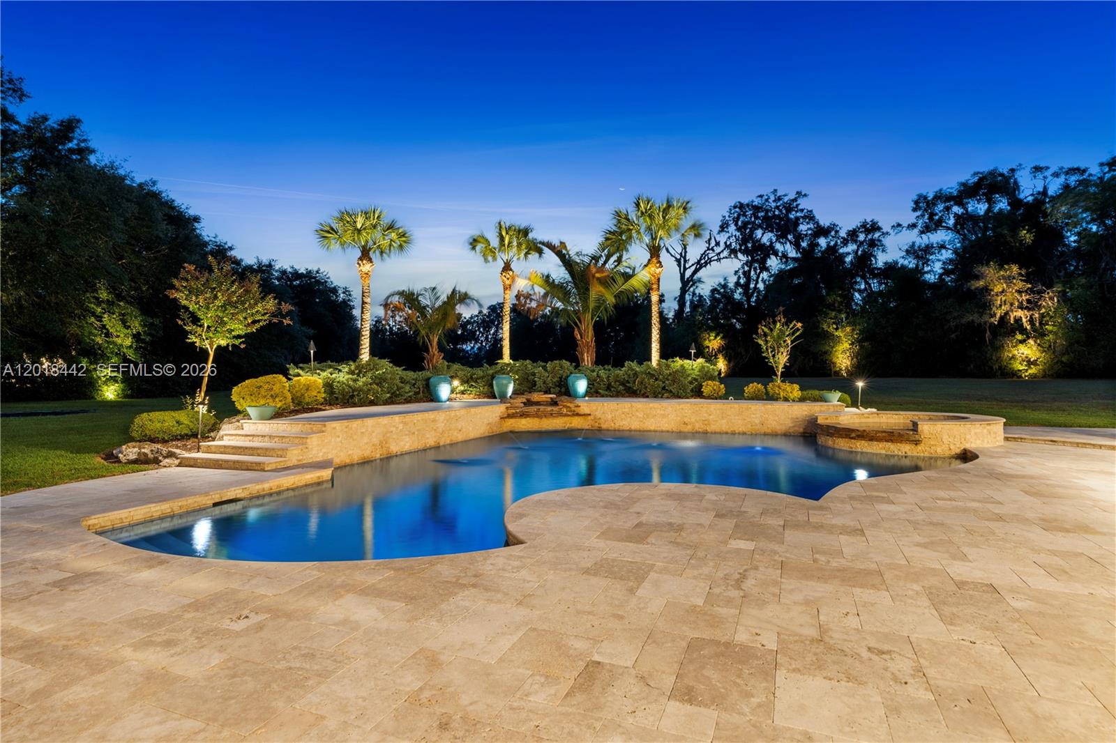 A swimming pool with a stone deck and water features sits before a landscaped yard — 15508 NW 45TH PLACE, Gainesville FL 32669, GAINESVILLE, FL