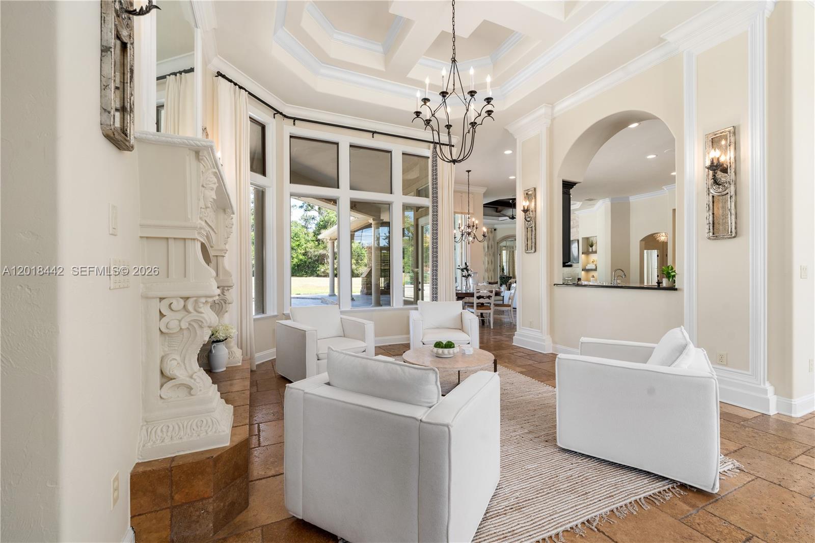 A living room features a stone fireplace, white armchairs, tile floors, and a coffered ceiling — 15508 NW 45TH PLACE, Gainesville FL 32669, GAINESVILLE, FL