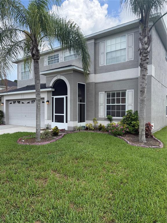 A two-story house with a gray stucco exterior, a screened entryway, and two palm trees — 31037 BACLAN DRIVE, WESLEY CHAPEL, FL