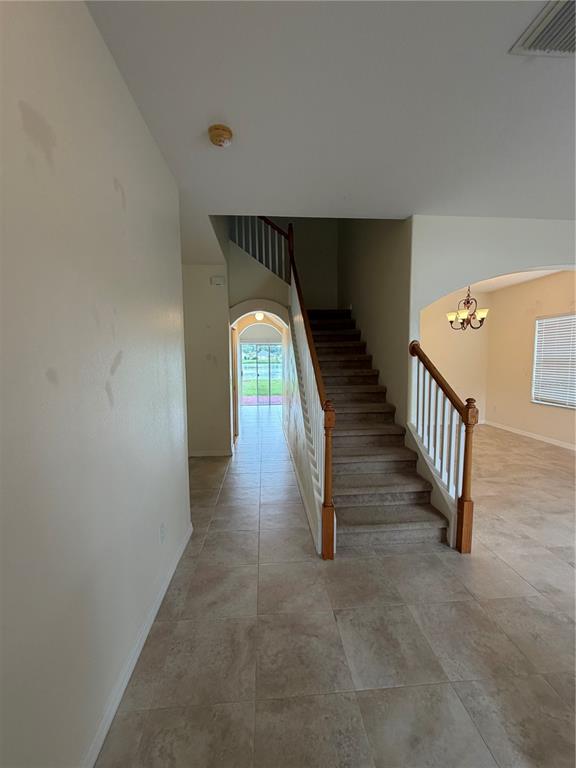 An entryway features tile flooring, a carpeted staircase with a wooden railing, and an arched doorway — 31037 BACLAN DRIVE, WESLEY CHAPEL, FL