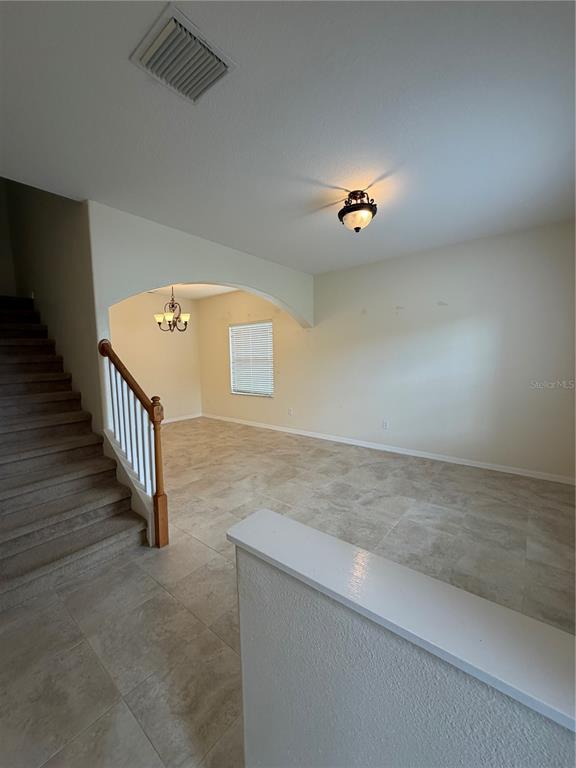 A staircase with carpeted steps leads to an open living area with tile flooring — 31037 BACLAN DRIVE, WESLEY CHAPEL, FL