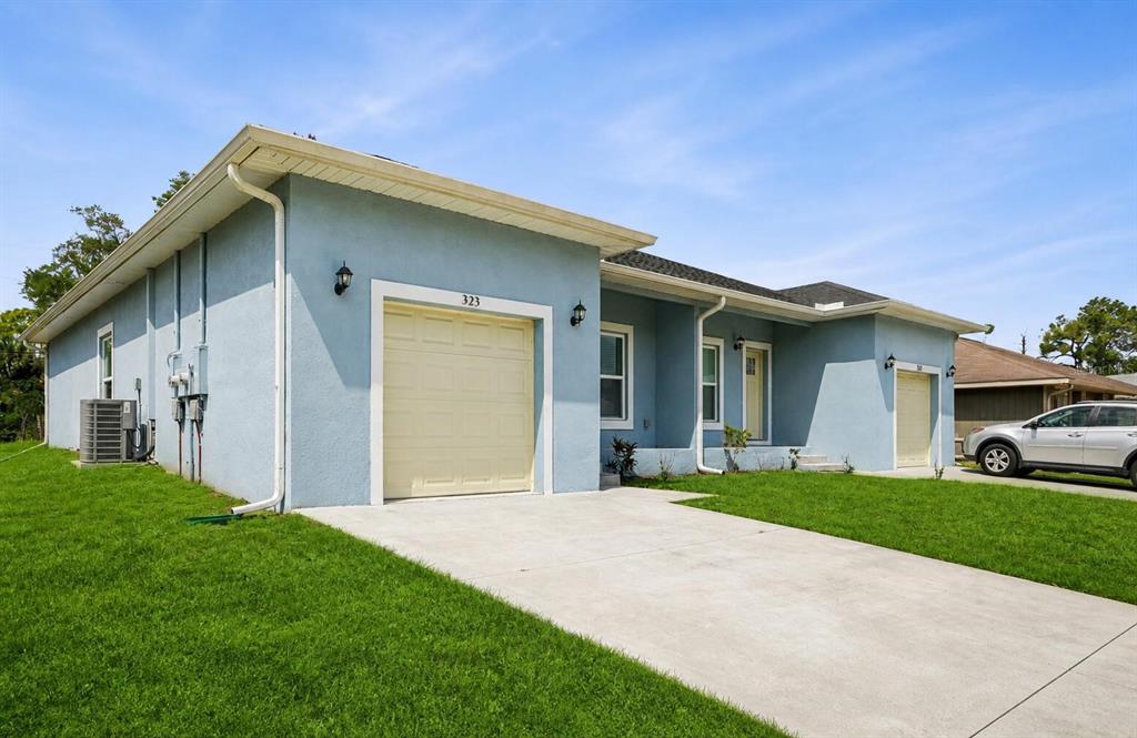 A light blue single-story house features two garage doors, a concrete driveway, and green lawn — 321 CAMILLIA LANE, PORT CHARLOTTE, FL