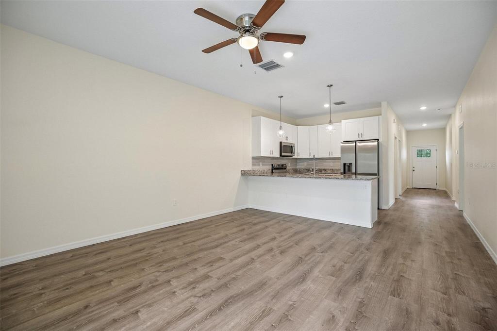 An open-concept kitchen with white cabinets and a breakfast bar overlooks a living area — 321 CAMILLIA LANE, PORT CHARLOTTE, FL