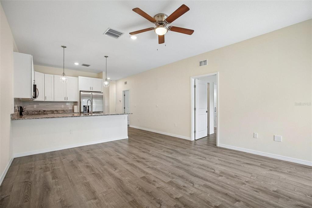 An open-concept kitchen and living area featuring white cabinets, granite countertops, and wood-look flooring — 321 CAMILLIA LANE, PORT CHARLOTTE, FL