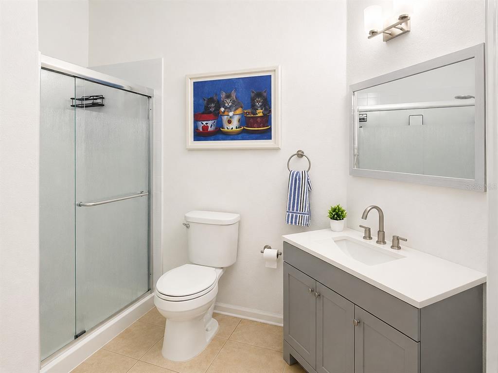 A bathroom features a glass-enclosed shower, a white toilet, and a gray vanity with a mirror — 3314 ROBERT TRENT JONES DRIVE UNIT 10401, ORLANDO, FL