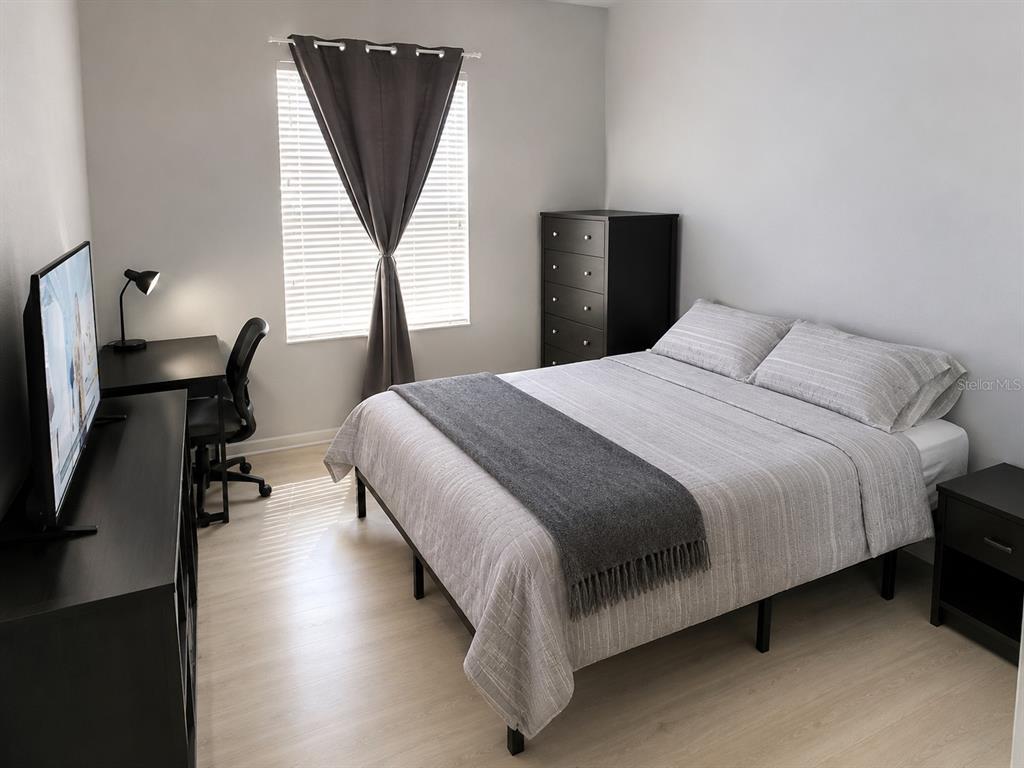 A bedroom features a bed with grey bedding, a dark dresser, a desk, and a window — 3314 ROBERT TRENT JONES DRIVE UNIT 10401, ORLANDO, FL