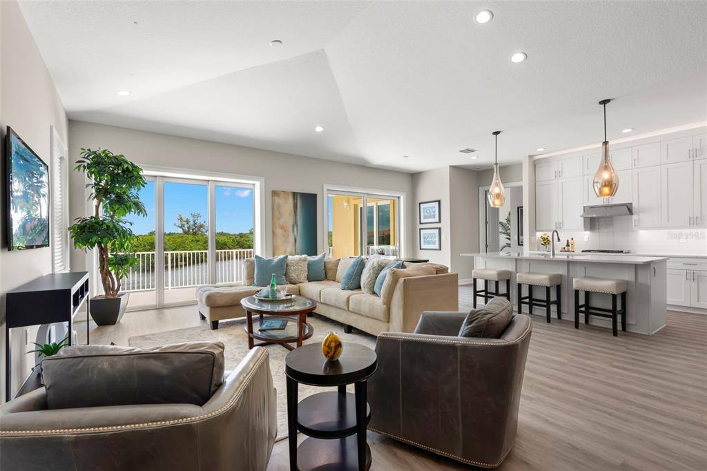 An open-concept living room and kitchen with white cabinetry, neutral furniture, and sliding glass doors — 47A BAYVIEW COURT S, ST PETERSBURG, FL
