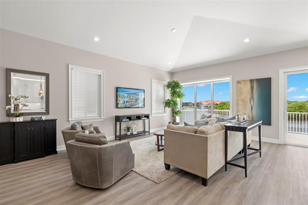 A living room features a vaulted ceiling, light wood flooring, and a view of water — 47A BAYVIEW COURT S, ST PETERSBURG, FL