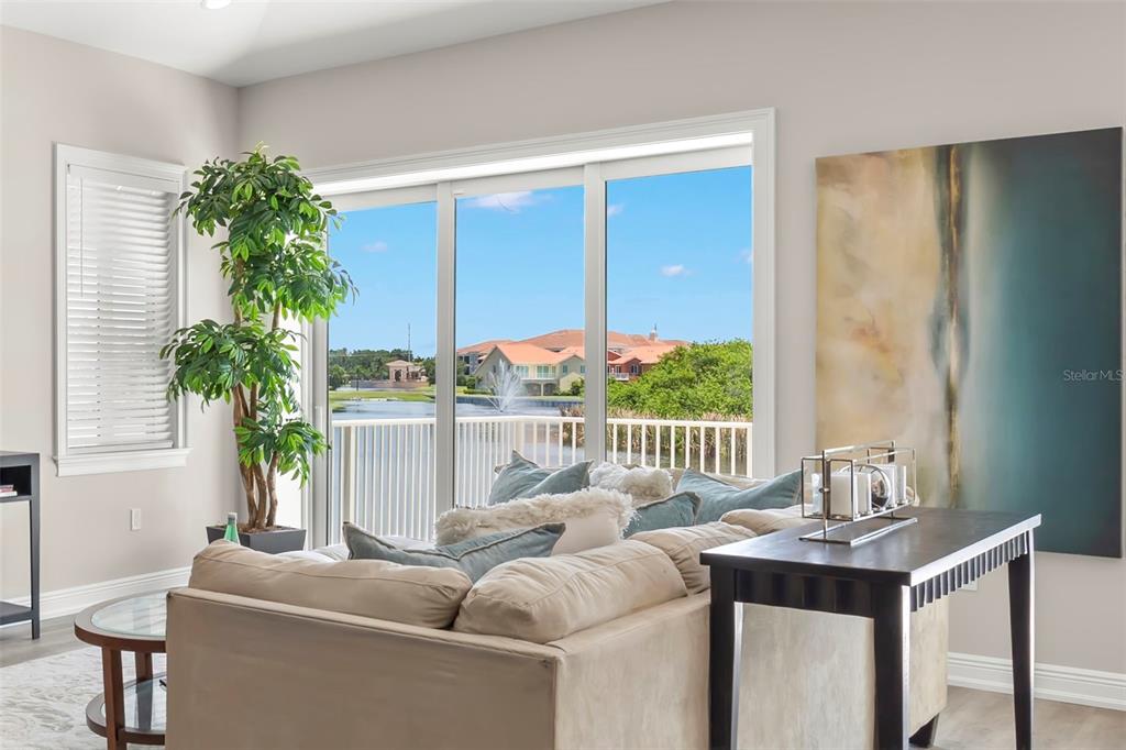 A living room features a beige sofa, a large potted plant, and a lake view — 47A BAYVIEW COURT S, ST PETERSBURG, FL
