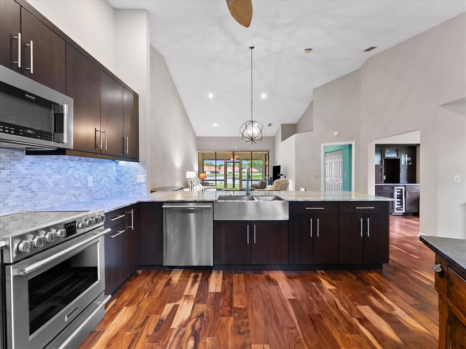 A modern kitchen features dark wood cabinets, stainless steel appliances, and hardwood floors — 7585 Lexington Club Boulevard # B, Delray Beach FL 33446, DELRAY BEACH, FL
