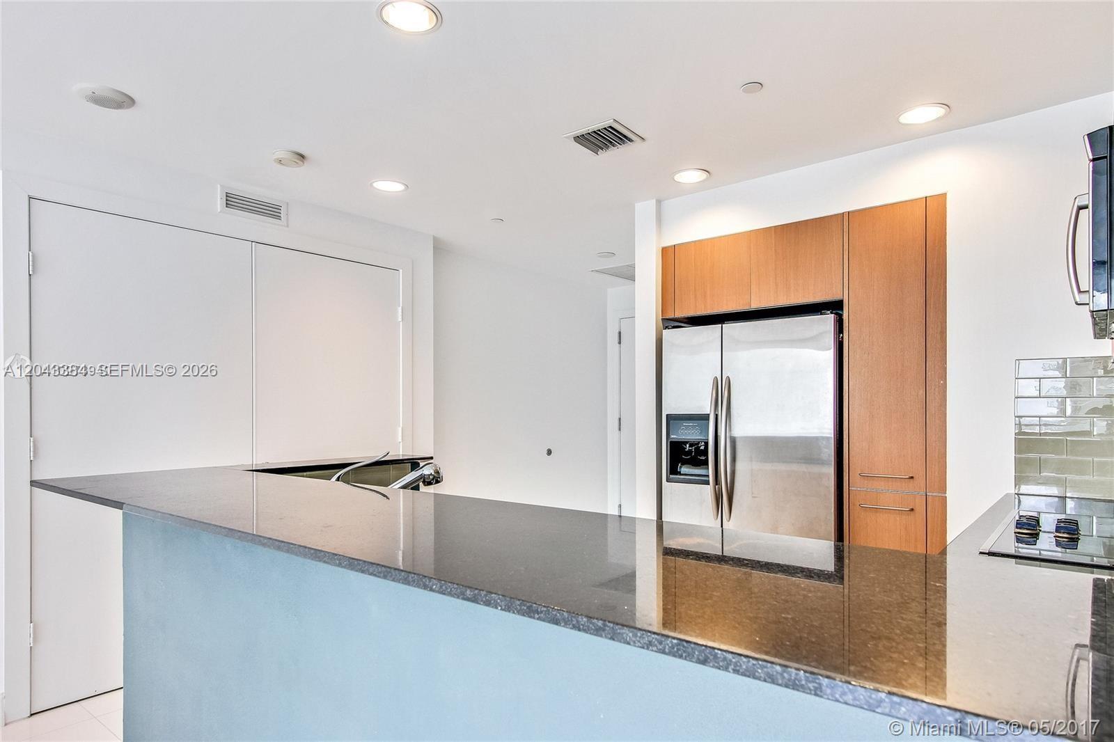 A minimalist room features white walls, white tile flooring, a sliding closet, and an open doorway — 1060 Brickell Ave # 2911, Miami FL 33131, MIAMI, FL