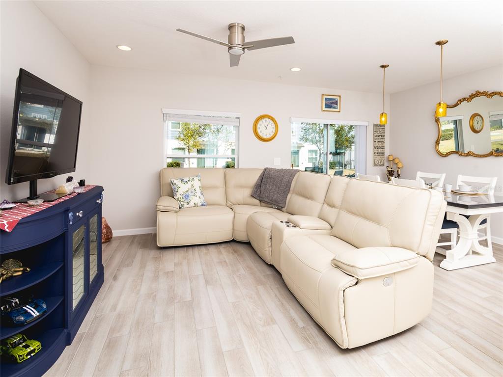 A living room with a beige sectional sofa, a blue media console, and dining area — 152 CAPE HONEYSUCKLE PLACE, SANFORD, FL