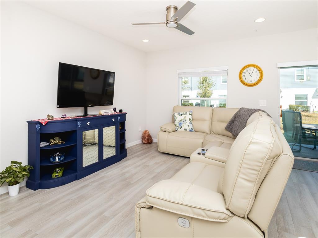 A living room features a blue media console, a beige sectional sofa, and light flooring — 152 CAPE HONEYSUCKLE PLACE, SANFORD, FL