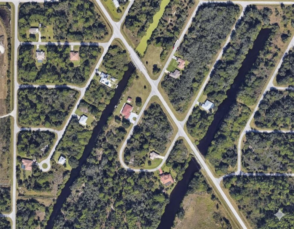 An aerial view shows houses situated on wooded lots separated by canals and paved roads — 2216 PRIVATE CIRCLE, PORT CHARLOTTE, FL