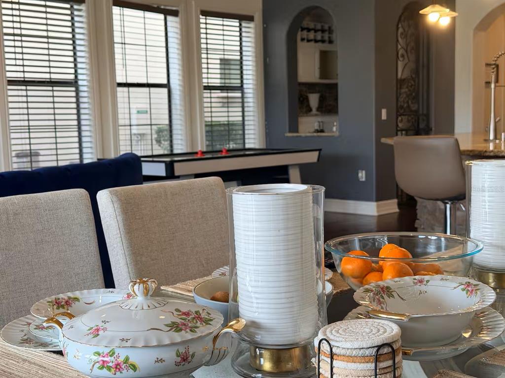 A dining area features a table set with floral china, a glass vase, and fruit — 841 DESERT MOUNTAIN COURT, REUNION, FL