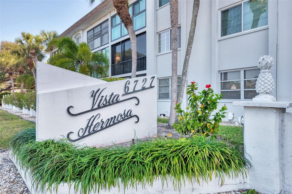 A white monument sign with the name Vista Hermosa stands in front of a multi-story building — 116 VISTA HERMOSA CIRCLE UNIT 210C, SARASOTA, FL