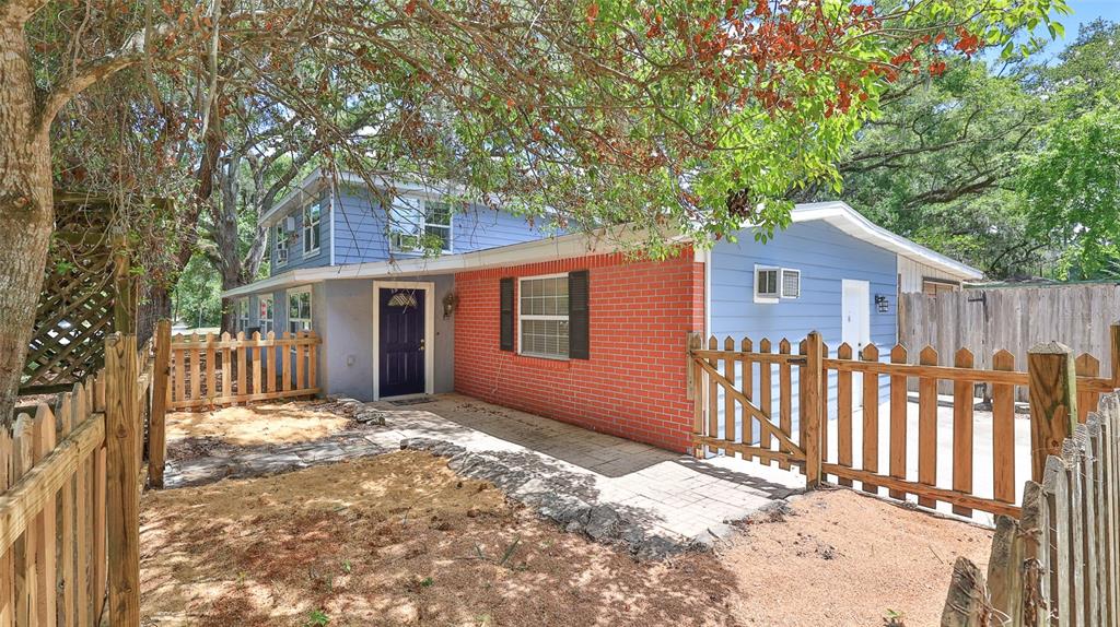 A two-story blue house with a red brick facade and a wooden picket fence — 801 E 20TH STREET, SANFORD, FL