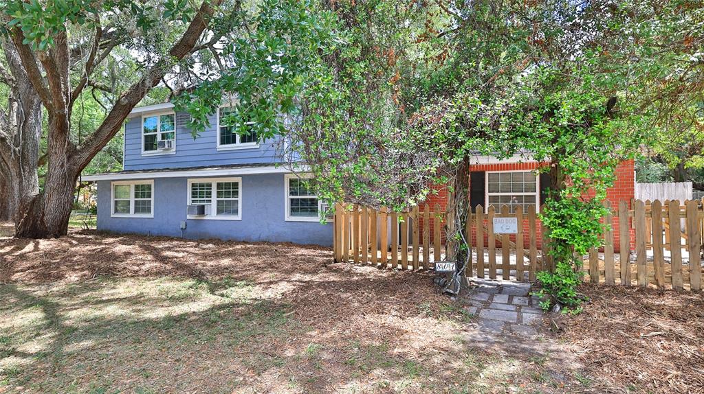 A two-story house with blue siding and red brick features a wooden fence and trees — 801 E 20TH STREET, SANFORD, FL