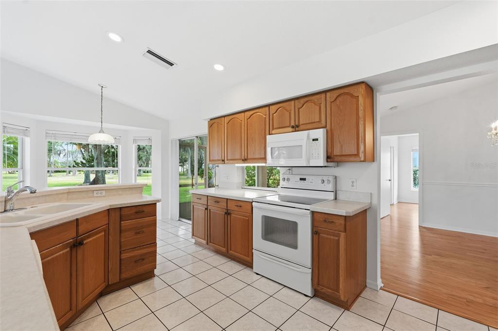 A bright living room features hardwood floors, a light-colored sofa, and a wooden front door — 1444 CANBERLEY COURT, TRINITY, FL