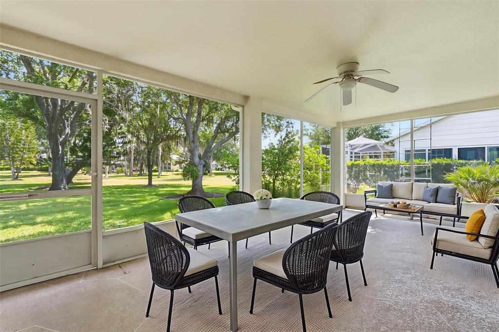 The exterior of a single-story house features a screened-in porch and large oak trees — 1444 CANBERLEY COURT, TRINITY, FL