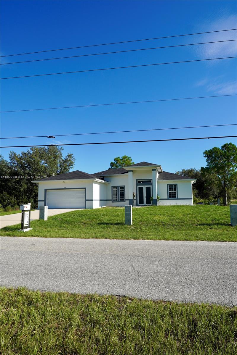 A single-story house with a white exterior, gray trim, and a two-car garage — 105 E 15th st, Lehigh Acres FL 33972, LEHIGH ACRES, FL